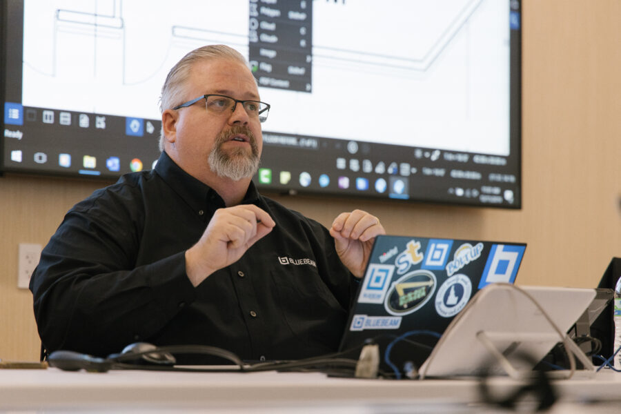 An instructor sits and trains with Bluebeam Revu software on the screen behind him.